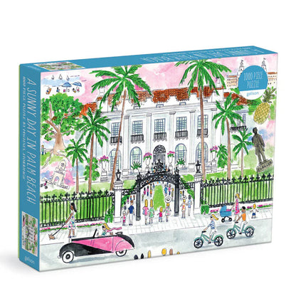 A Sunny Day in Palm Beach 1000-piece puzzle by Galison illustrated by Michael Storrings, featuring a stately mansion, palm trees, classic cars, and people strolling or cycling.