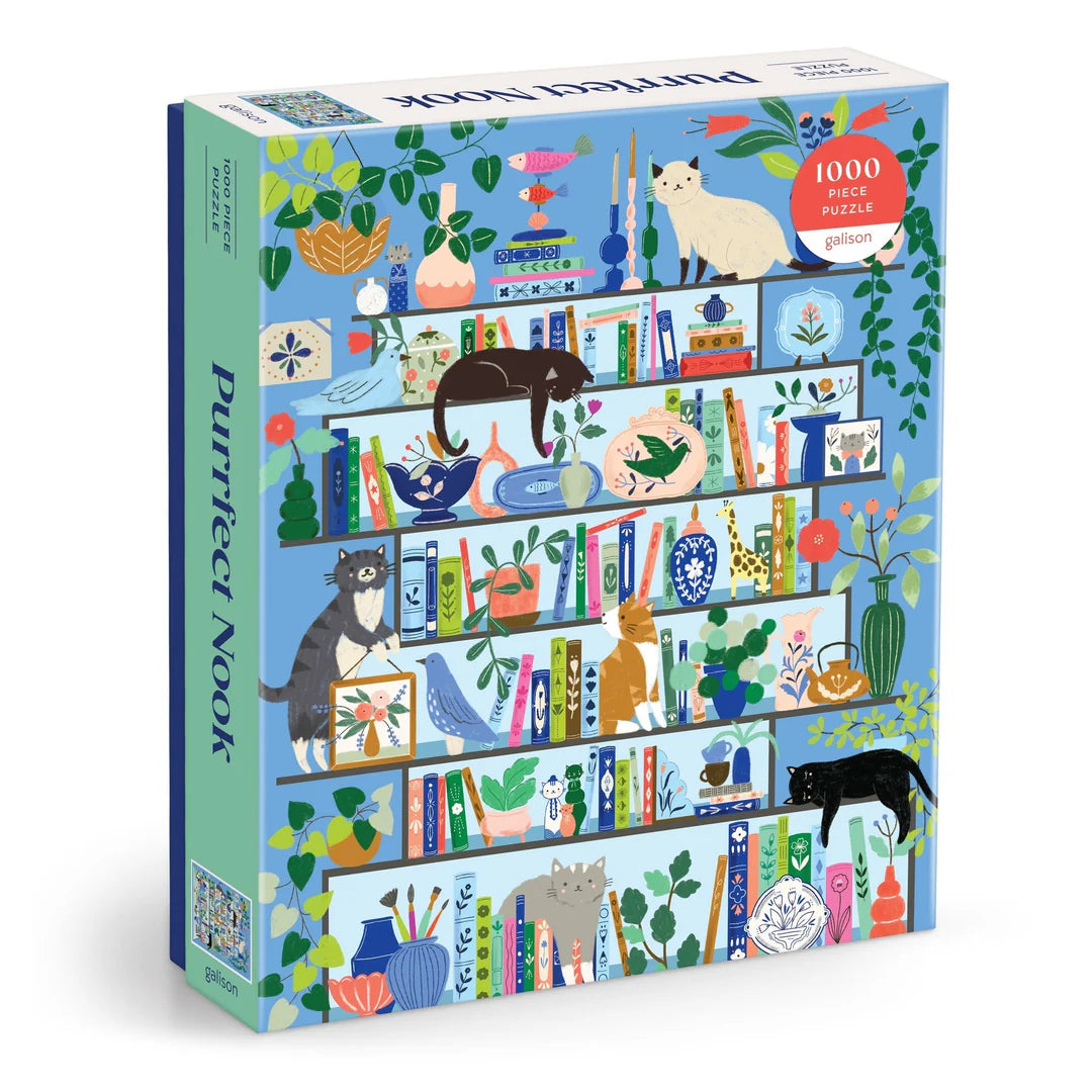 Purrfect Nook 1000-piece puzzle by Galison featuring illustrated cats lounging on colorful bookshelves filled with books, plants, and decorative objects.